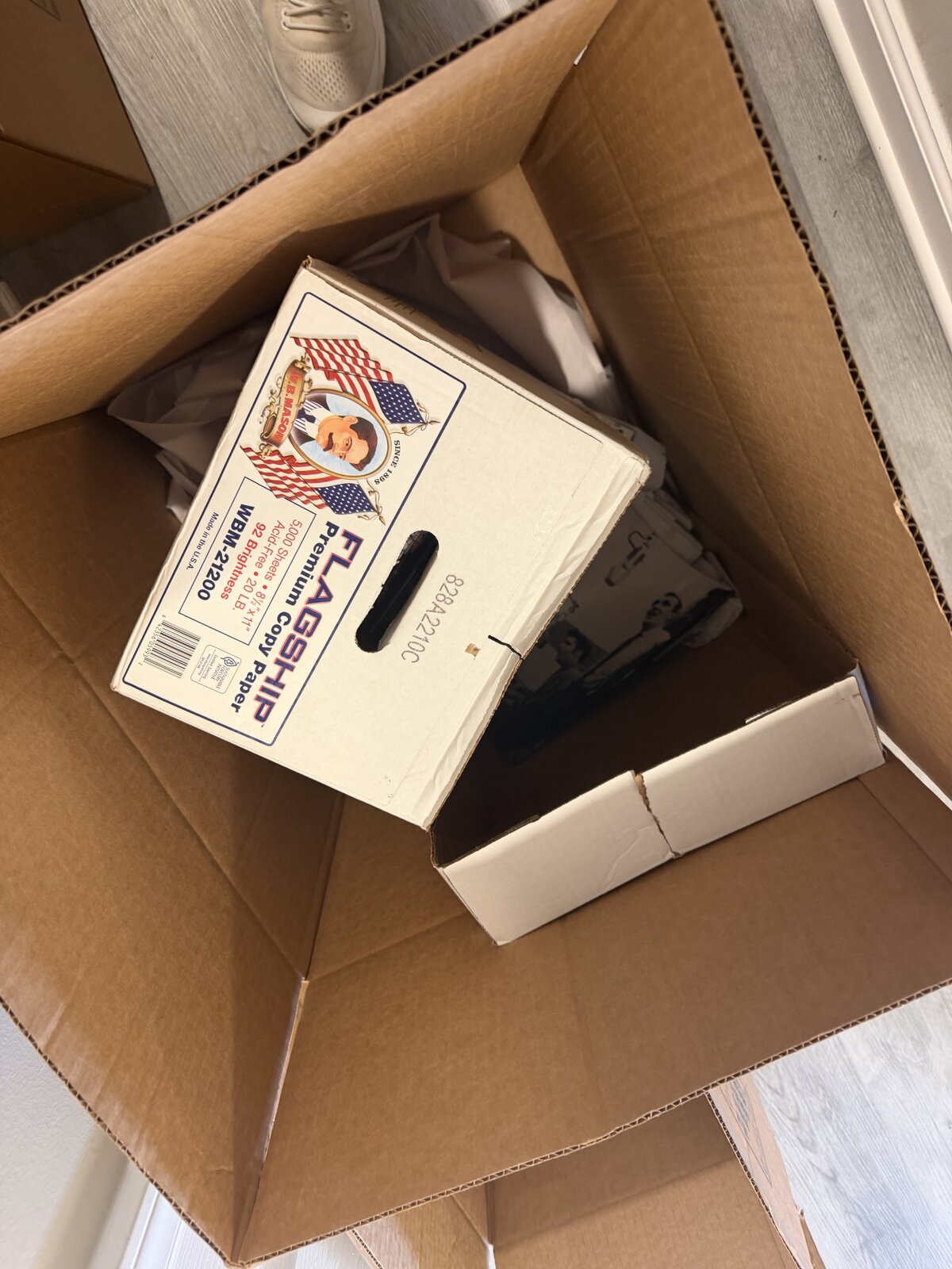 A half-full copy-paper box set loosely inside a larger moving box