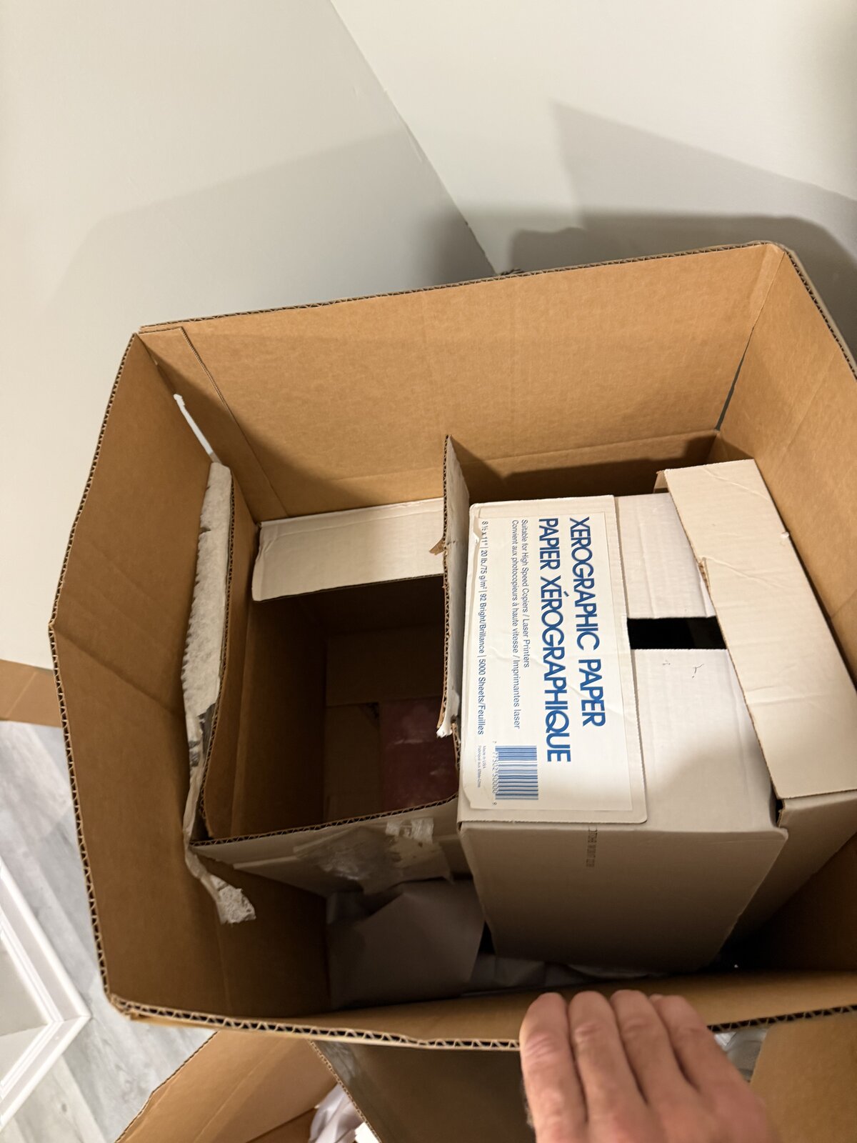One empty box and a half-full copy-paper box inside a medium moving box