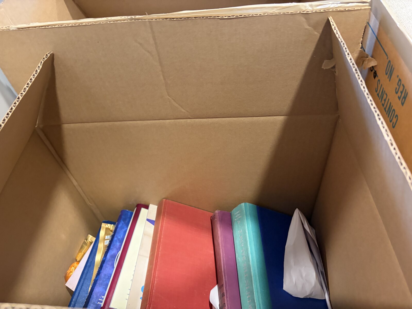 A single layer of books at the bottom of a small moving box