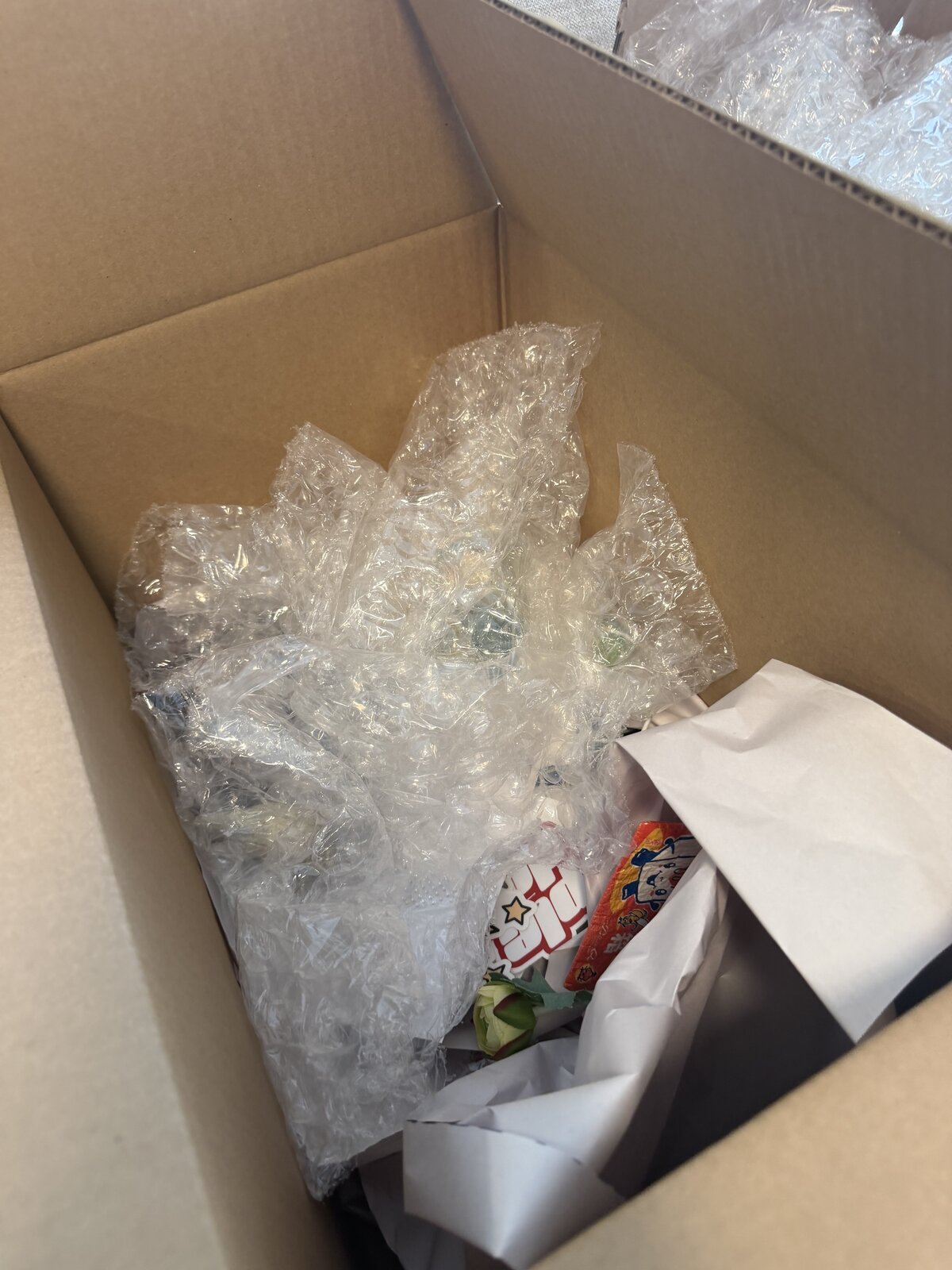 A small box filled almost entirely with bubble wrap around a few small items