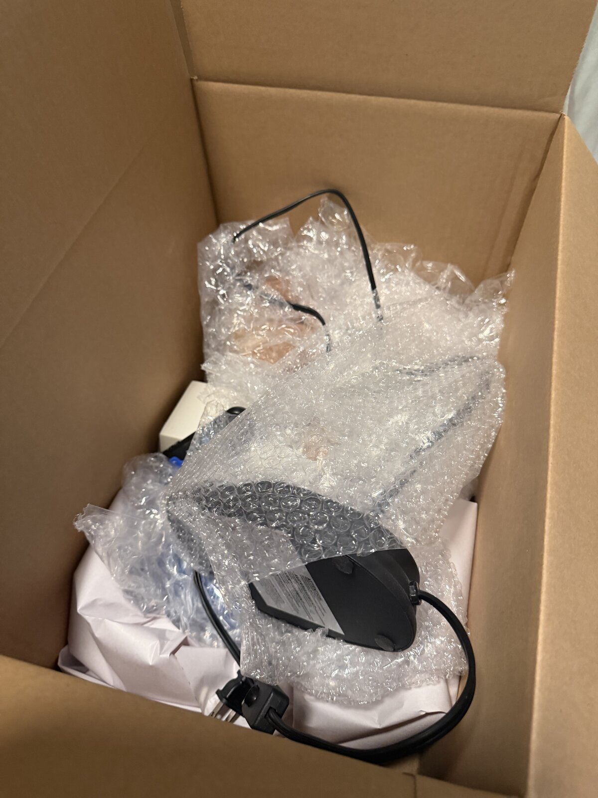 A single small electronic device surrounded by bubble wrap in a small box