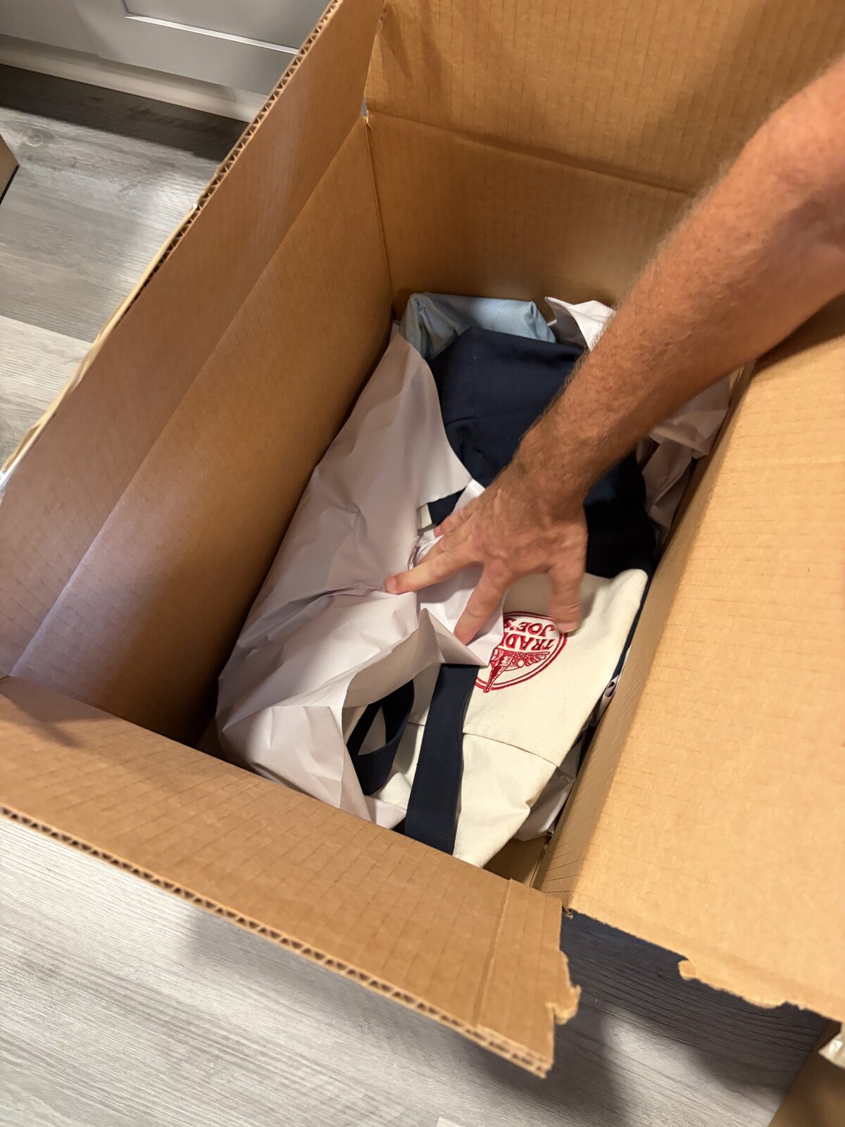 Three linen shopping bags and tissue paper in a small box, a hand reaching in