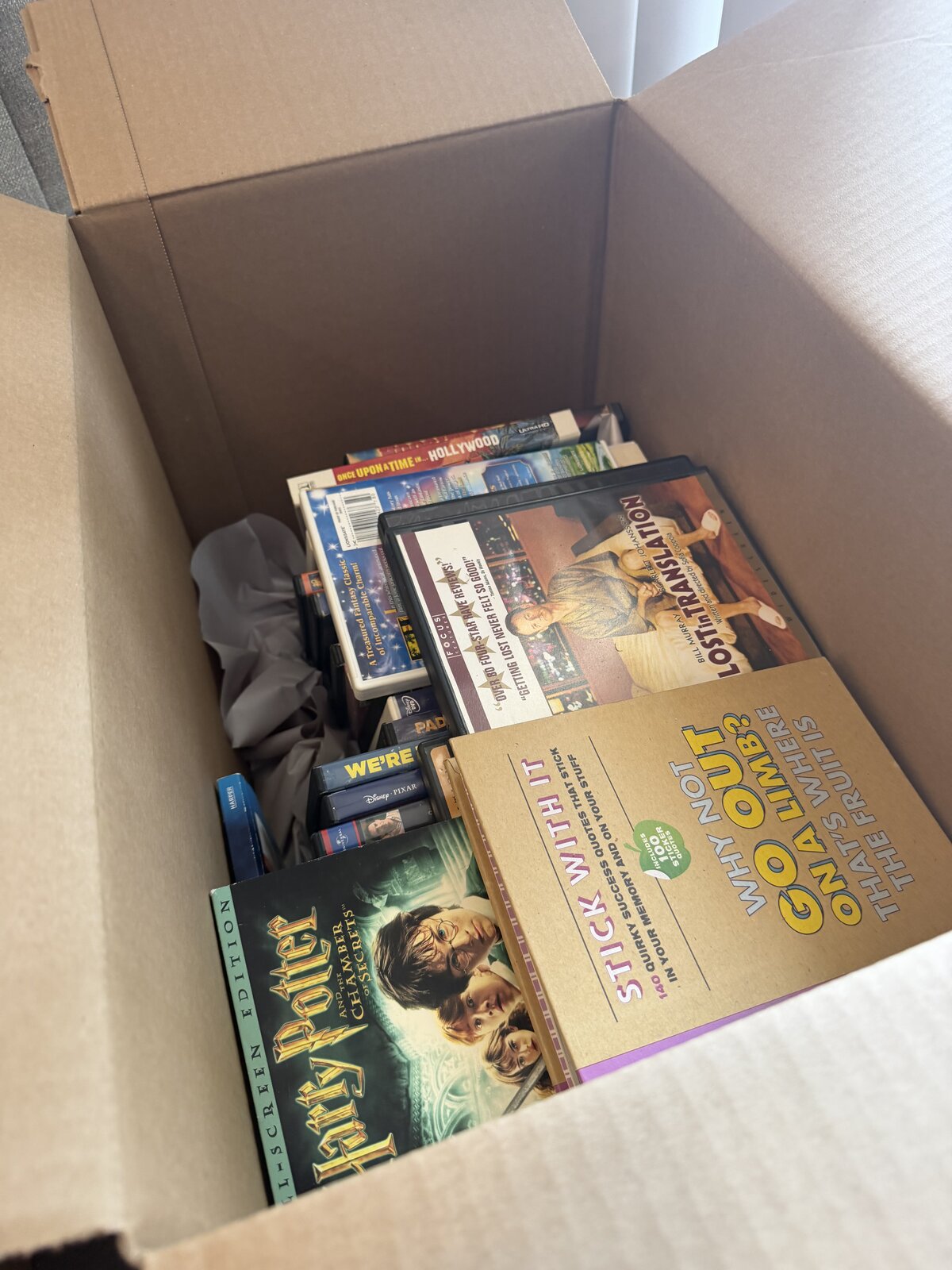 A box of DVDs, video games, and books