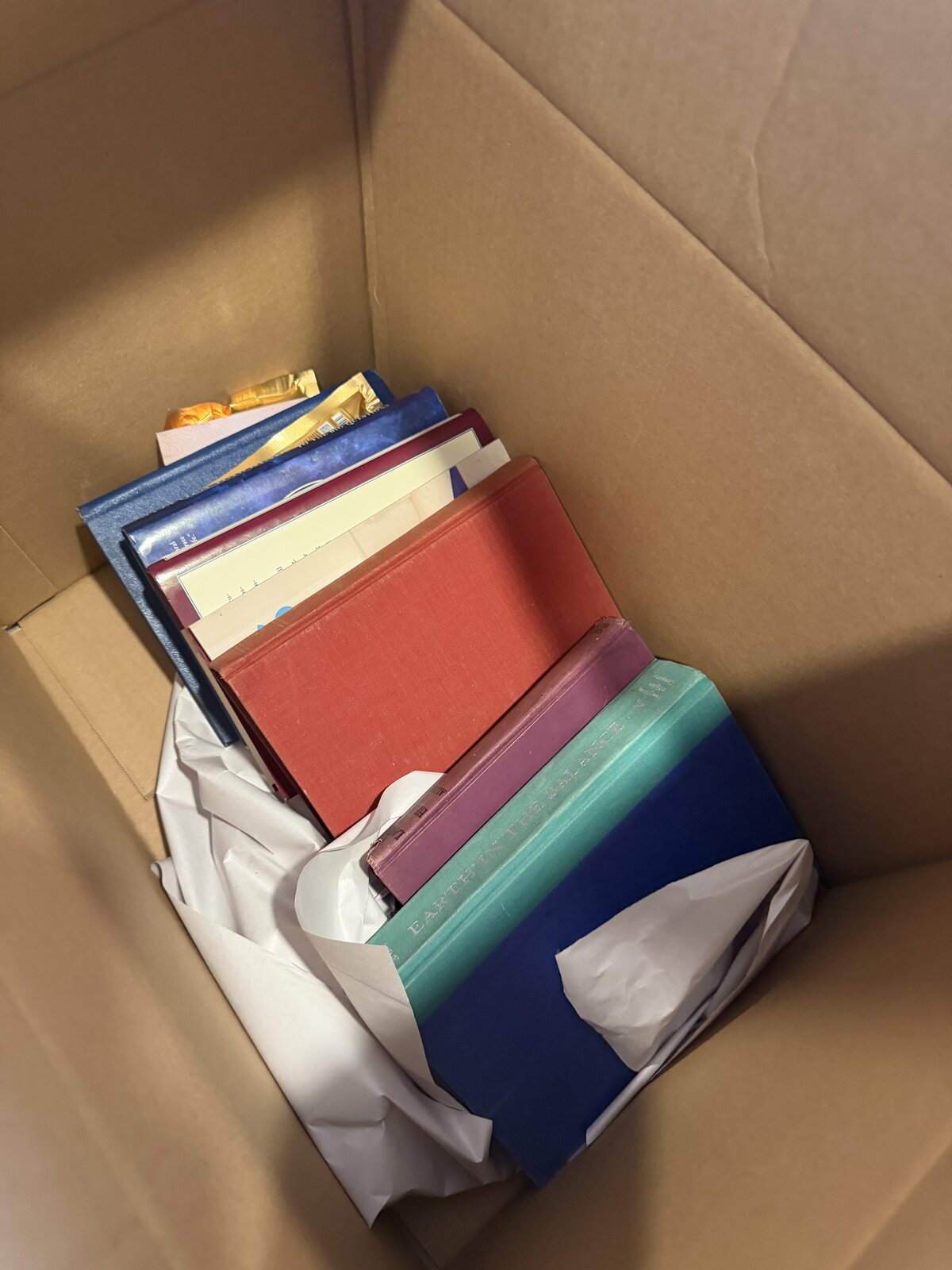 A partial layer of hardcover books with tissue paper in a small box